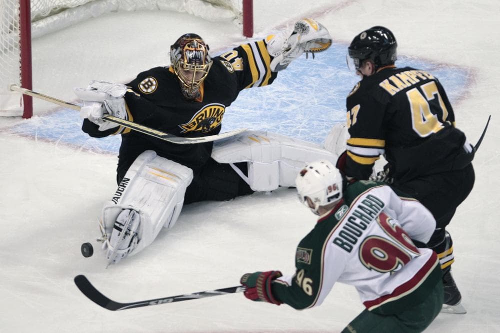 Boston goalie Tuukka Rask, of Finland, left, drops to the ice to make a save as Minnesota center Pierre-Marc Bouchard (96) looks for the rebound during the first period of the game on Thursday in Boston. At top right is Bruins defenseman Steve Kampfer. (AP)