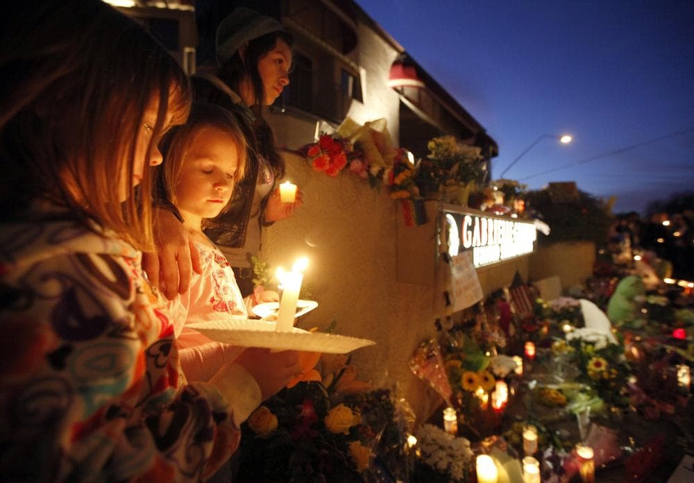From left, Ellie Steve, 6, Lucia Reeves, 6, and Zoe Reeves, 18, gather for a candlelight vigil outside the offices U.S. Rep. Gabrielle Giffords, D-Ariz., in Tucson, Ariz. (AP)