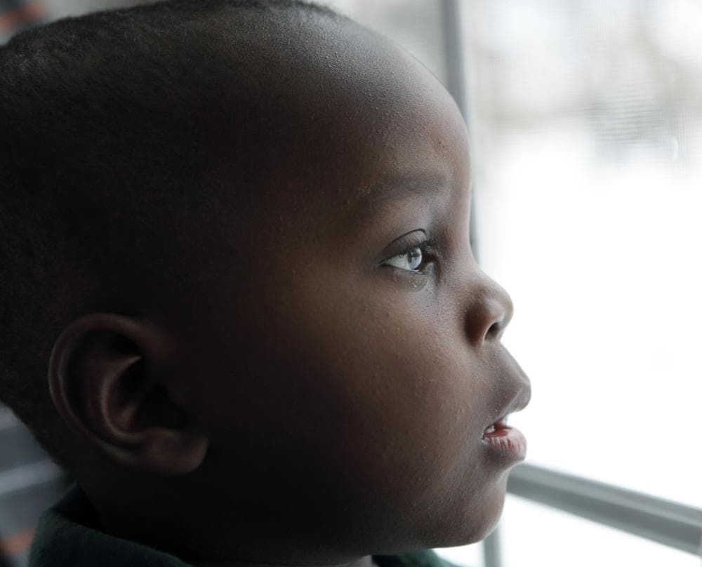 Sevil Fletcher, born in Haiti, looks out the window at his new home in Penfield, N.Y. after he was adopted by an American family. (AP)