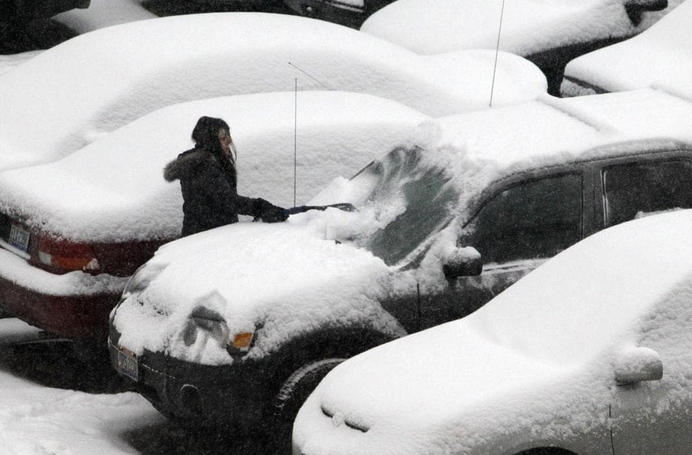 A woman clears fresh snow from her car in downtown Cleveland, Ohio parking lot. (AP)