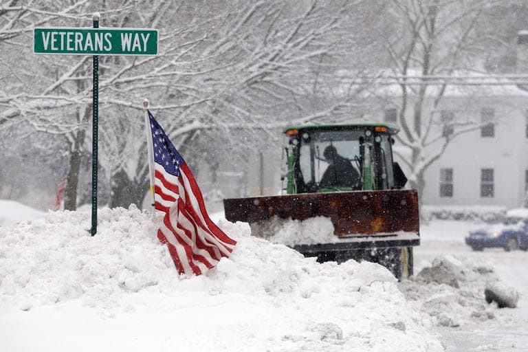 A bucket loader moves snow off the town square in Norwell on Friday. (AP)