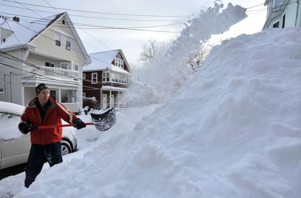 Kevin Andrew adds to the pile of snow on his front yard as he clears his driveway in Somerville on Thursday. (AP)