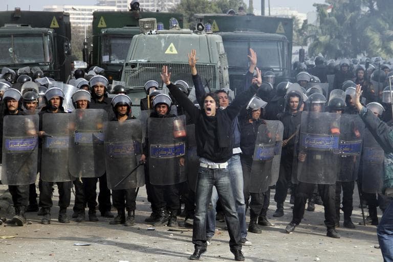 Egyptian protesters shout in front of anti-riot policemen who block a bridge in Cairo, Egypt, Friday. (AP)