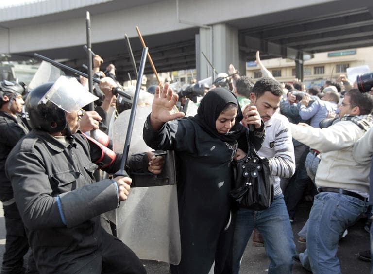 An Egyptian woman flees as Egyptian anti-riot policemen clash with protesters in Cairo, Egypt, Friday, Jan. 28, 2011. (AP)
