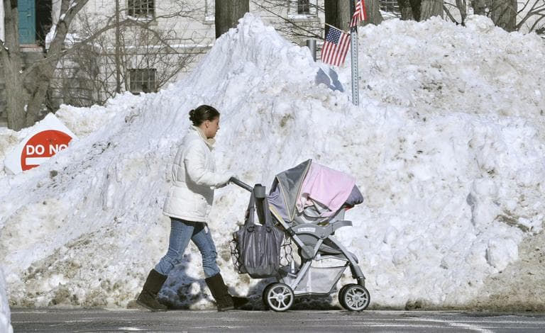 A pedestrian, forced into the street by blocked sidewalks, passes piles of snow outside Massachusetts General Hospital in Boston on Thursday. (AP)