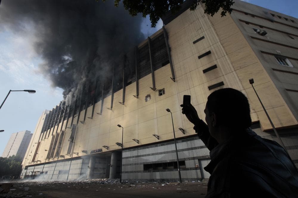 An Egyptian man uses his mobile phone to take a picture of the Arcadia shopping center, that was looted, damaged and set on fire by people in Cairo, Egypt, Sunday Jan. 30, 2011. (AP Photo/Lefteris Pitarakis)