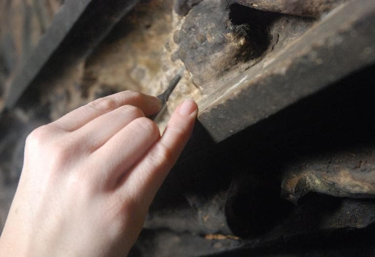 Holly Salmon uses a scalpel to flake off caked-on soot from the 15th century fireplace.