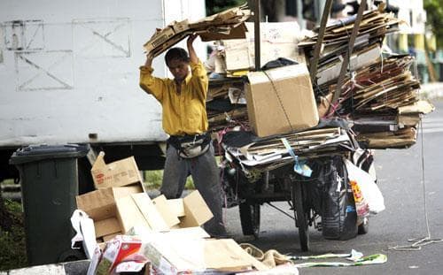 An unemployed man in Singapore collects cardboard waste to exchange for money along a residential area, Jan. 5, 2011. (AP)
