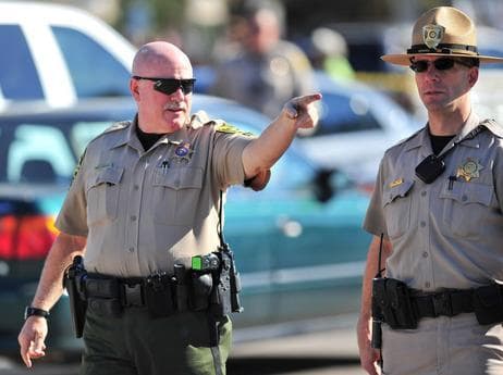 A sheriff speaks to another officer at the scene of the shooting in Tucson, Ariz. on Saturday. (AP)