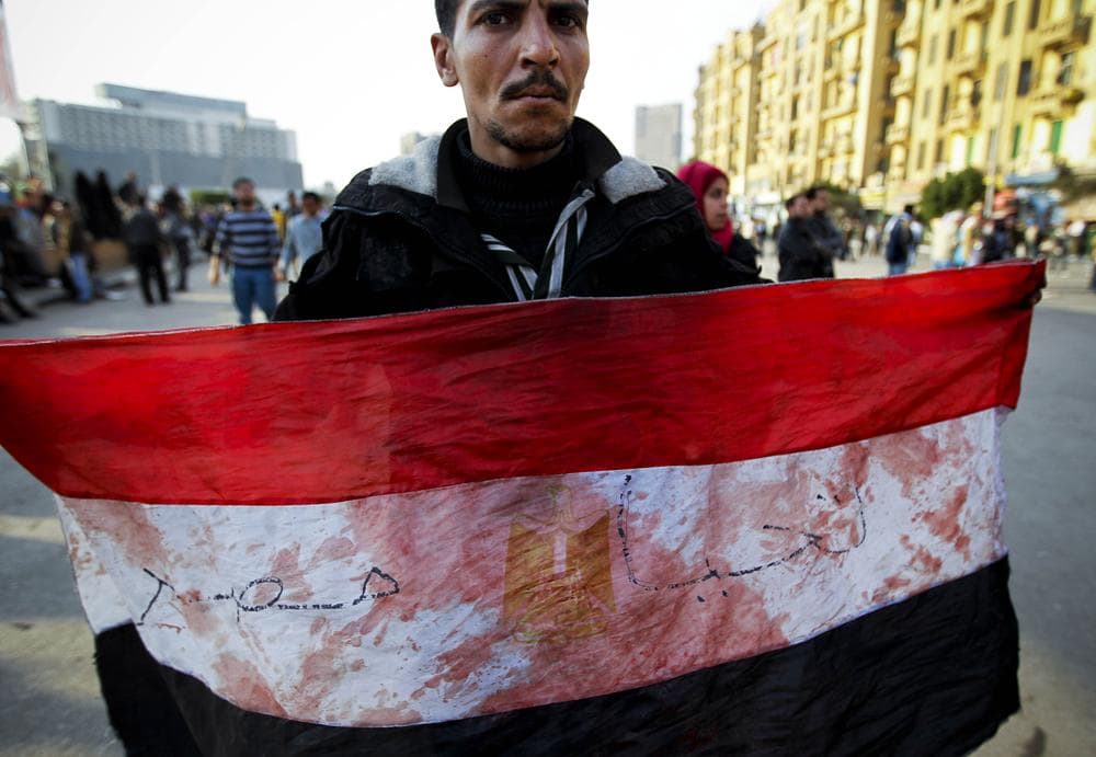 An anti-government protester displays an Egyptian flag, covered with blood, during clashes in Tahrir, or Liberation square, in Cairo, Egypt. (AP)