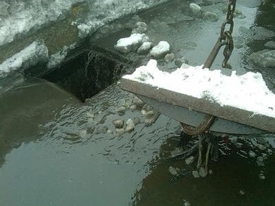 Crews pull up a snow-clogged storm drain. (Steve Brown/WBUR)