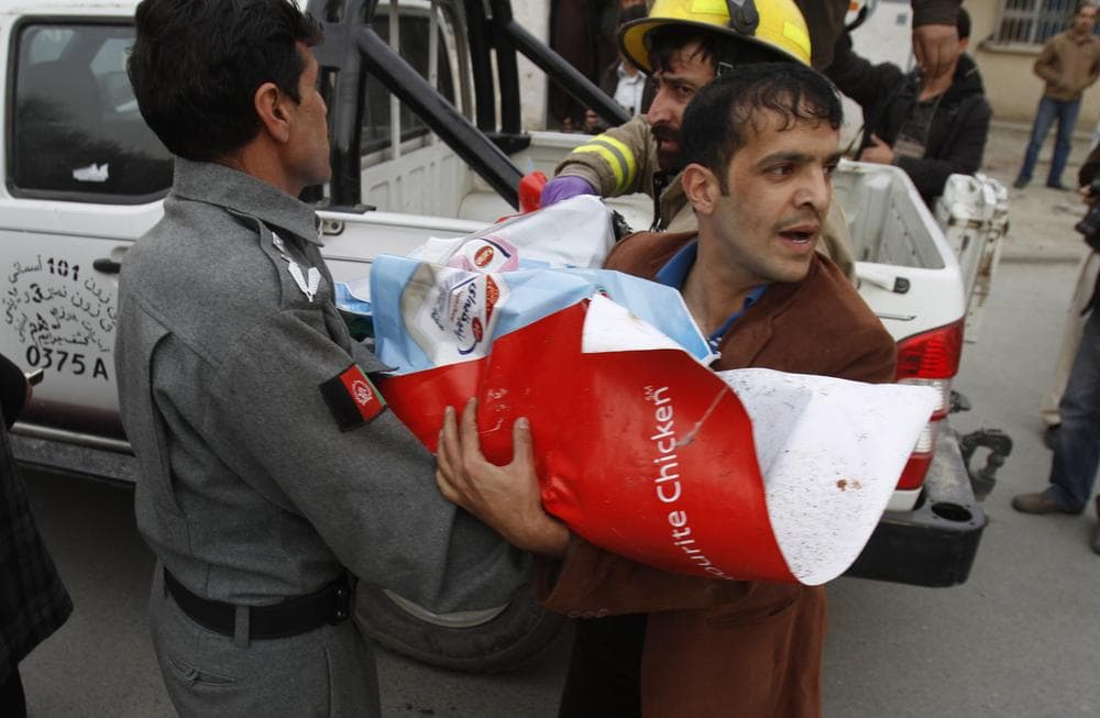 The body of a child wrapped in posters is brought out of a supermarket Jan. 28, 2011 in central Kabul, Afghanistan. A bomb exploded inside a grocery store frequented by foreigners on Friday in Kabul, killing 14. (AP)