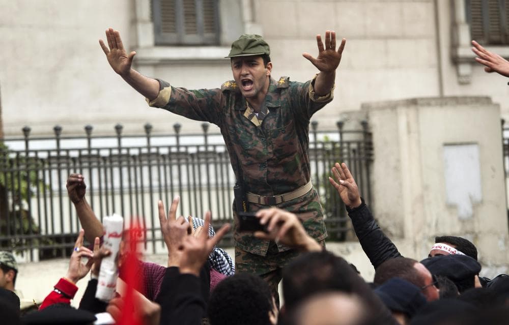 An Egyptian Army soldier tries to calm down the crowd as protesters demonstrate near Tahrir Square in downtown Cairo, Egypt, Sunday, Feb. 13, 2011. Egypt's military has started taking down the makeshift tents of protesters who camped out on Tahrir Square in an effort to allow traffic and normal life to return to central Cairo. (AP Photo/Emilio Morenatti)