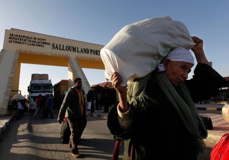 Egyptians who fled Libya carry their belongings through the Salloum land port gate at the Egyptian-Libyan border on Tuesday. (AP)