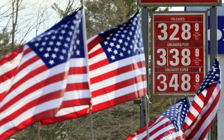 American flags blow in the wind outside a Gibbs gas station in Topsham, Maine, where a sign shows the new price of gasoline. (AP)