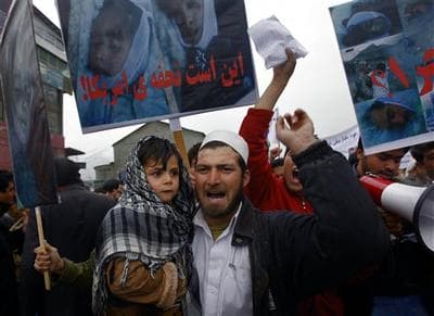 An Afghan supporter of left wing political party holds his son as he shouts anti US slogans during a protest in Kabul, Afghanistan. Poster reads in Arabic '&quot;Gift of America.&quot; (AP)