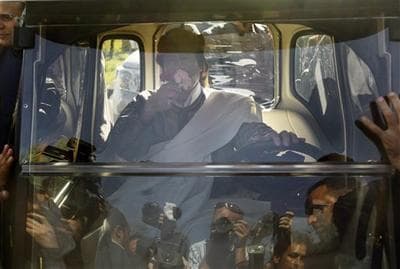 Libyan Leader Moammar Gadhafi smells flowers given to him by a supporter as he drives away in an electric golf cart after speaking in Tripoli, Libya, Wednesday, March 2, 2011. (AP)