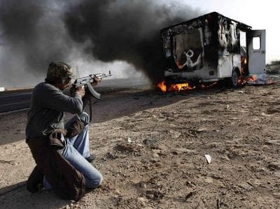 A Libyan rebel took aim at a burning vehicle used by pro-Moammar Gadhafi fighters in celebration of the rebel victory in Wednesday's battle for Brega. (AP)