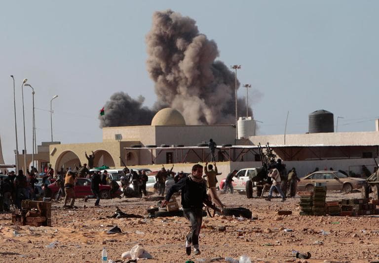 An anti-Gadhafi rebel runs away as smoke rises following an airstrike by Libyan warplanes in Ras Lanouf, eastern Libya, on Monday. (AP)