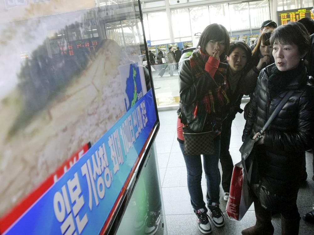 Japanese tourists watch a TV news program about a strong earthquake hitting their country at Seoul Railway Station in Seoul, South Korea on Friday. (AP)