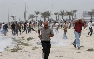 Anti-government protesters react to tear gas fired by riot police along a main highway in Manama, Bahrain. (AP)
