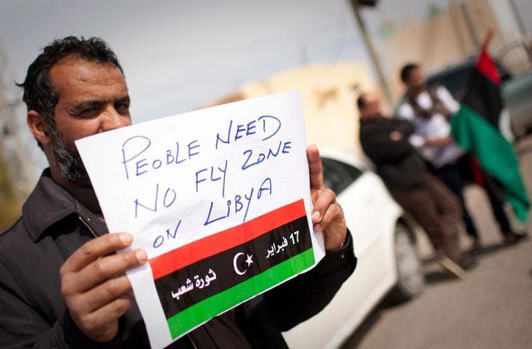 A Libyan man holds up a sign asking for a no-fly zone over Libya near the border town of Musa&#039;id, Libya, on Sunday. (AP)