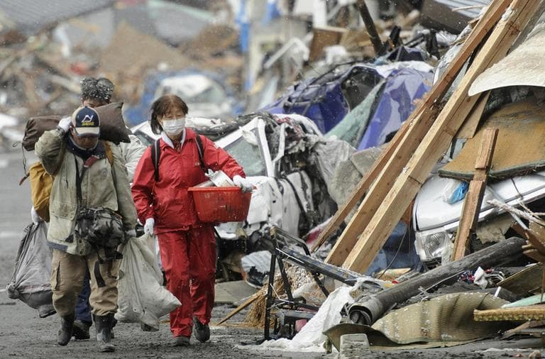 Survivors of Friday's earthquake and tsunami walk with their belongings by the rubble in Kamaishi in northern Japan. (AP)