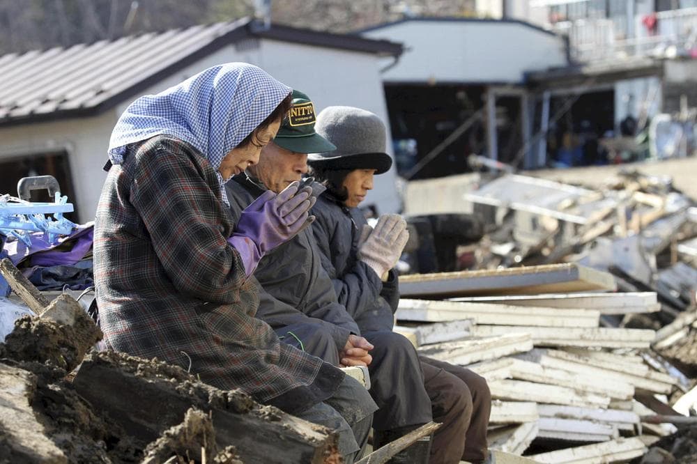 Survivors pray for victims at the devastated city of Miyako, northeastern Japan. (AP/Yomiuri Shimbun, Naoya Masuda)