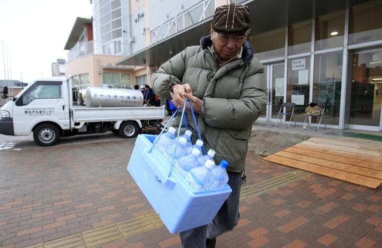 A man carries bottled water he got from a supply water tank in Chiba prefecture, near Tokyo, Japan, after the government issued a warning of elevated levels of radioactive iodine in tap water. (AP)