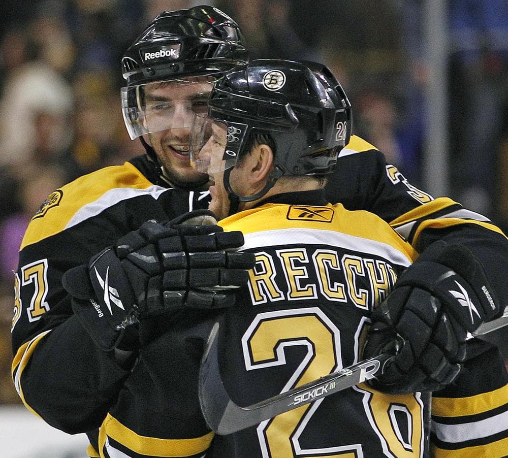 Boston Bruins center Patrice Bergeron (37) hugs left wing Mark Recchi (28) after Recchi's assist on a Boston goal against the Chicago Blackhawks in the second period of the game in Boston on Tuesday. The Bruins won 3-0. (AP)
