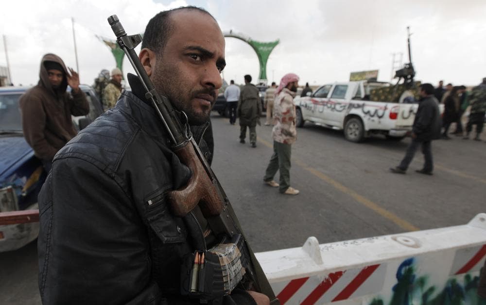 A Libyan rebel fighter guards the roadway to the western gate of Ajdabiya, Libya. (AP)