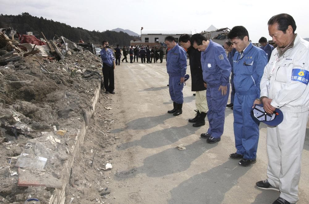 In this photo released by Prime Minister's Official Residence, Japanese Prime Minister Naoto Kan, third right, dressed in the blue work clothes, observes a minute of silence as he inspects the damage in the March 11 earthquake and tsunami devastated city of Rikuzentakata, Iwate Prefecture, northern Japan Saturday. (AP) 