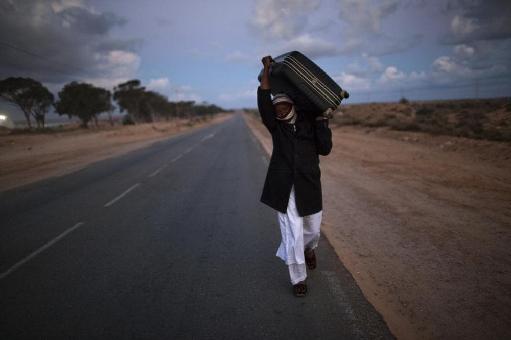 A man from Ghana, who used to work in Libya and fled the unrest in the country, carries his belongings as he arrive in a refugee camp after crossing from Libya at the Tunisia-Libyan border, in Ras Ajdir, Tunisia.  (AP)
