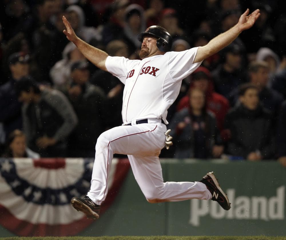 Boston's Kevin Youkilis goes flying into home to score on a double by teammate David Ortiz during the eighth inning of their 4-0 win over New York in the game at Fenway Park in Boston on Sunday. (AP)