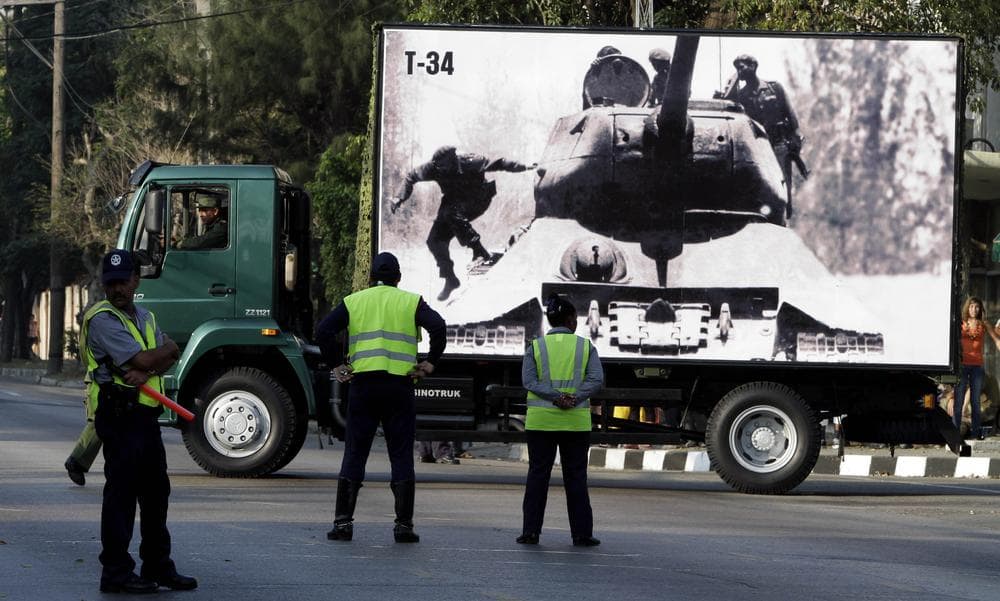 Police watch a truck carrying an April 1961 photograph of Cuba's leader Fidel Castro jumping from a tank, left, near the Bay Of Pigs, during rehearsals for an upcoming parade commemorating the 50th anniversary of the Bay of Pigs in Havana, Cuba. (AP)