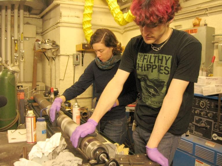 MIT grad students Alessondra Springmann and Nathan Lachenmyer repair part of the Kendall Band at a university machine shop. (Sacha Pfeiffer/WBUR)