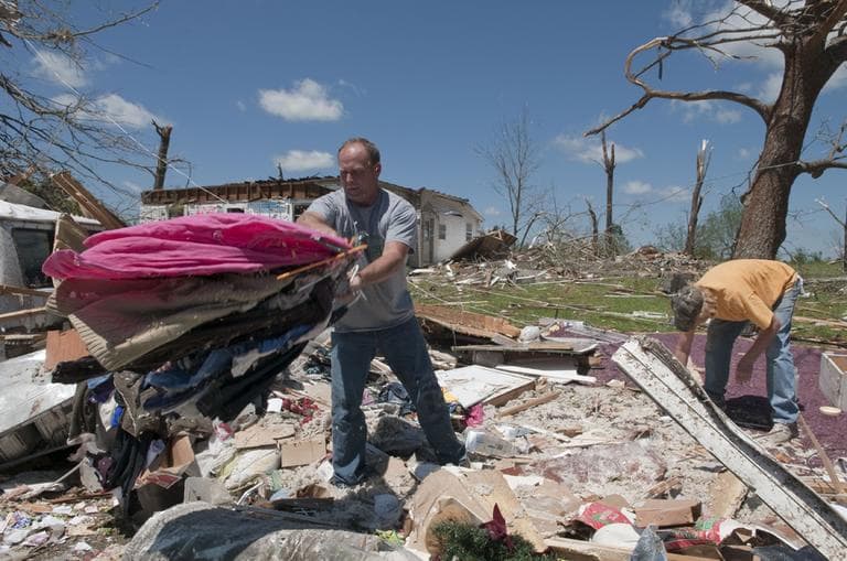 Mark Plunkett, left, with the help of Allen Southerland, right, find some of his wife's clothing in the debris of his Phil Campbell home Thursday. (AP)