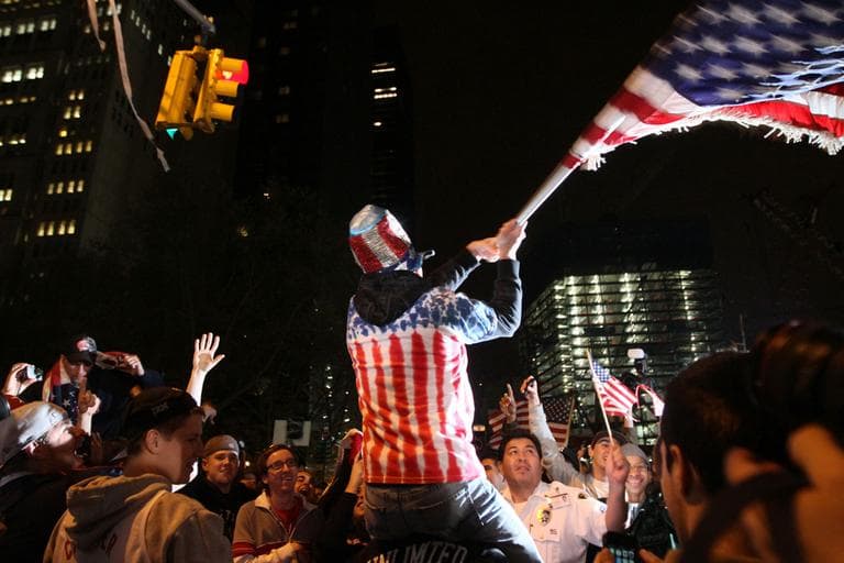Perched on another's shoulders, Ryan Burtchell, of Brooklyn, waves an American flag over the crowd as they celebrate the news of Osama Bin Laden's death early Monday morning near ground zero in New York. (AP)