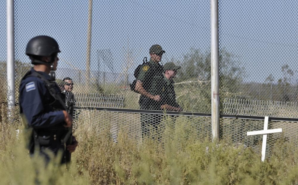 A federal police officer, left, stands guard as U.S. law enforcement officers look on from the U.S. side of the fence in Ciudad Juarez, Mexico. (AP)