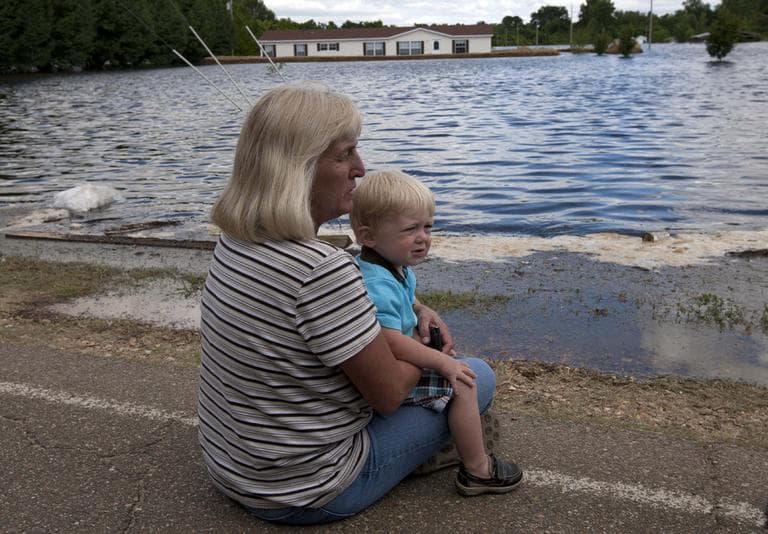 Debra Emery holds her grandson Cayden Peebles as she watches floodwater rise around her mobile home in Vicksburg, Miss., Monday. (AP)