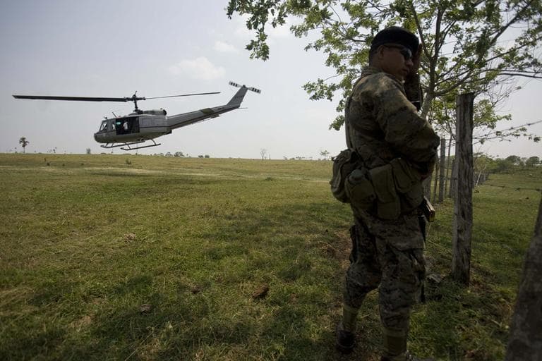 A soldier stands guard as a helicopter takes off at the site of a massacre at a ranch in La Bomba, northern Guatemala, Monday.
