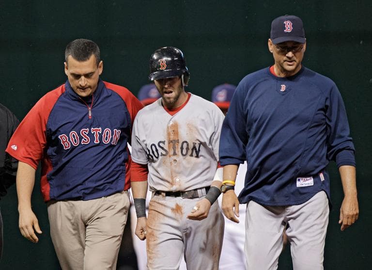 Boston Red Sox's Dustin Pedroia, center, walks off the field with assistant trainer Greg Barajas, left, and manager Terry Francona after an injury in the eighth inning against the Cleveland Indians on Monday in Cleveland. (AP)