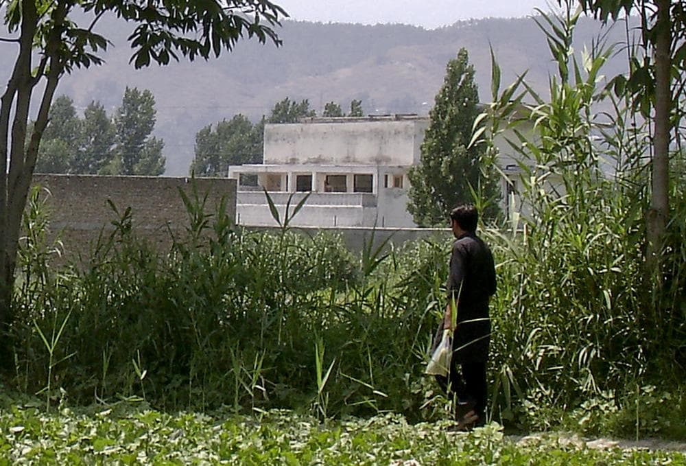 A local residents walks near a house, seen at centre, on Wednesday, where al-Qaida leader Osama bin Laden was caught and killed in Abbottabad, Pakistan. (AP)