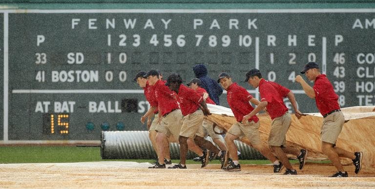 The grounds crew dashes across the infield as heavy rain falls during the third inning of the interleague game between the Boston Red Sox and San Diego Padres on Wednesday. (AP)