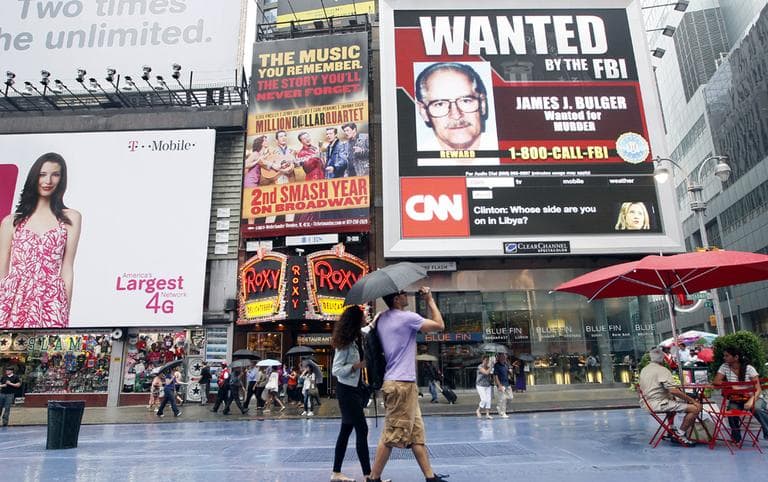 A couple walks past an FBI video looking for mob boss James &quot;Whitey&quot; Bulger on display in New York&#039;s Times Square,  Thursday, June 23, 2011. (AP)