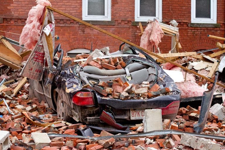 Bricks and debris cover a parked car in the South End area of Springfield. (Jesse Costa/WBUR) 