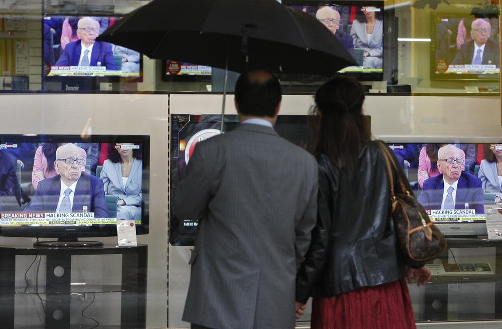 Pedestrians look at television screens, showing Chairman of News Corporation Rupert Murdoch during a select committee on the phone hacking scandal, outside a electronics shop in London, Tuesday. (AP)