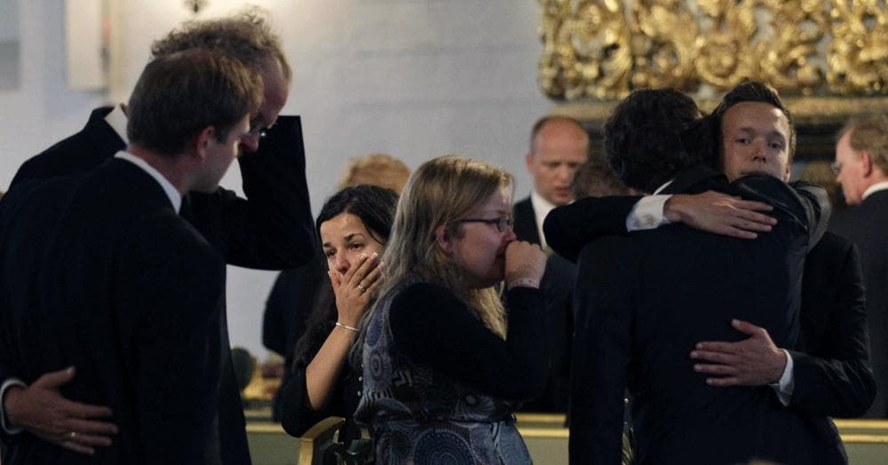 A woman covers her mouth as people embrace during a memorial service at Oslo Cathedral. (AP) 