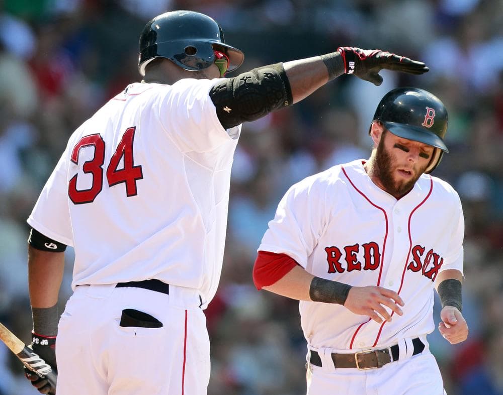 Boston Red Sox&#039;s David Ortiz, left, taps Dustin Pedroia on the helmet after Pedroia scored on a single by Adrian Gonzalez in the sixth inning of the game against the Seattle Mariners in Boston on Sunday. Pedroia extended his hitting streak to 21 games with a double in the sixth. The Red Sox won 12-8. (AP)