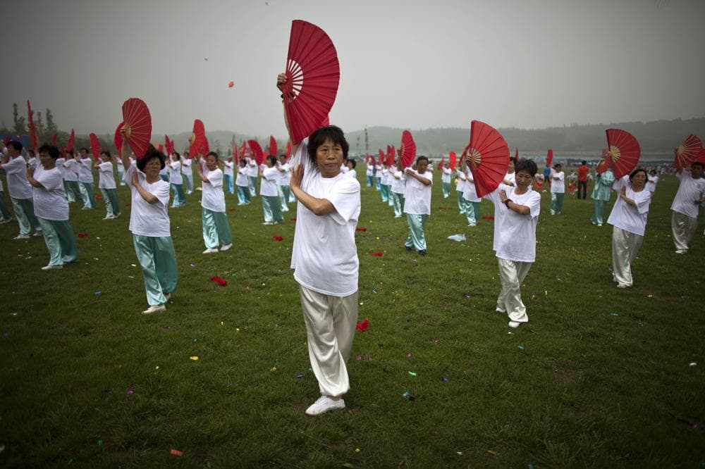Women perform a fan dance during a ceremony of a government campaign to promote physical exercises at Beijing's Olympic Forest Park in China. (AP)